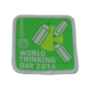 Ein Quadratisches Abzeichen mit grünem Hintergrund, mit drei grünen Stilisierten Stiften darauf. Darunter steht "World thinking day 2014"